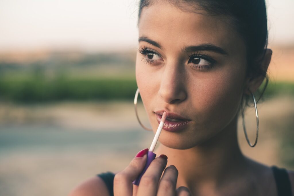 Portrait of teenage girl applying lip gloss